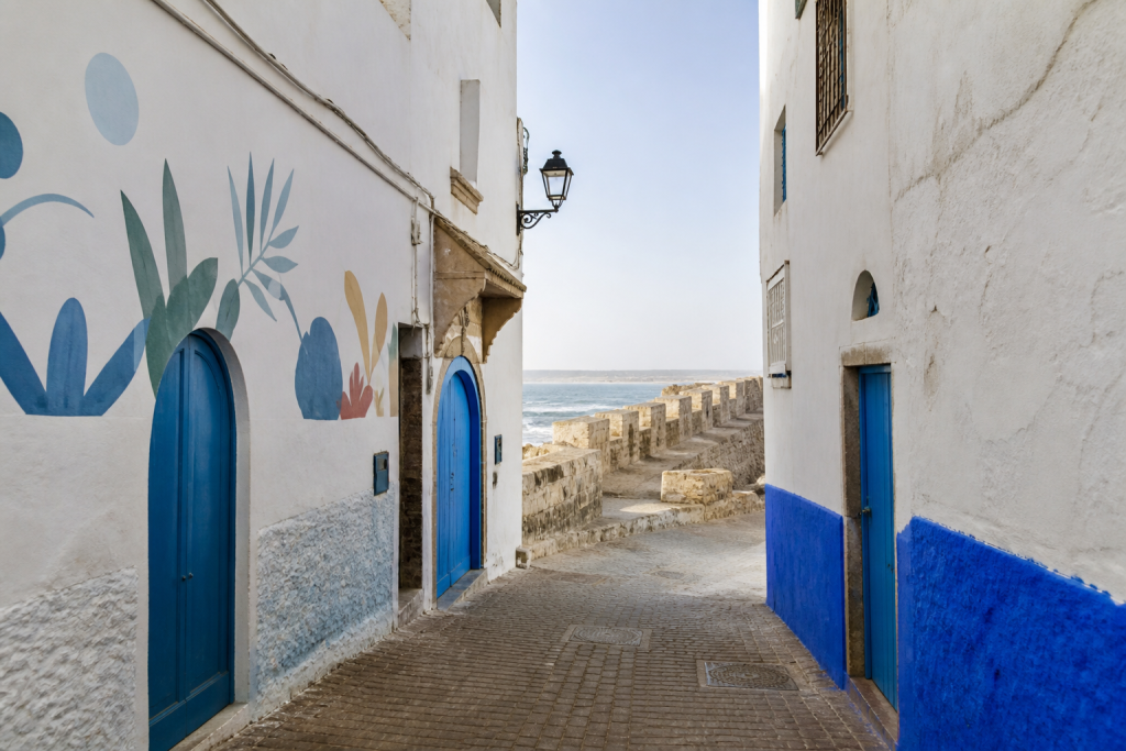White and blue Asilah lane opening towards the Atlantic ramparts