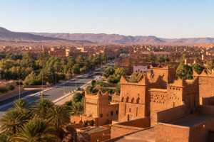 Ouarzazate with earthen architecture, palms, an avenue and arid hills