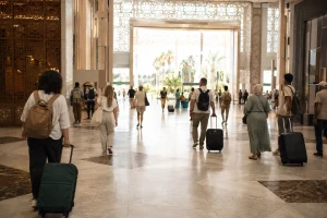 Voyageurs avançant calmement dans un hall d’arrivée marocain lumineux avec leurs bagages
