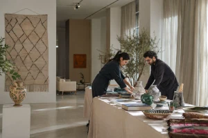 Deux professionnels préparent une table d’exposition consacrée aux cultures marocaines dans un espace contemporain